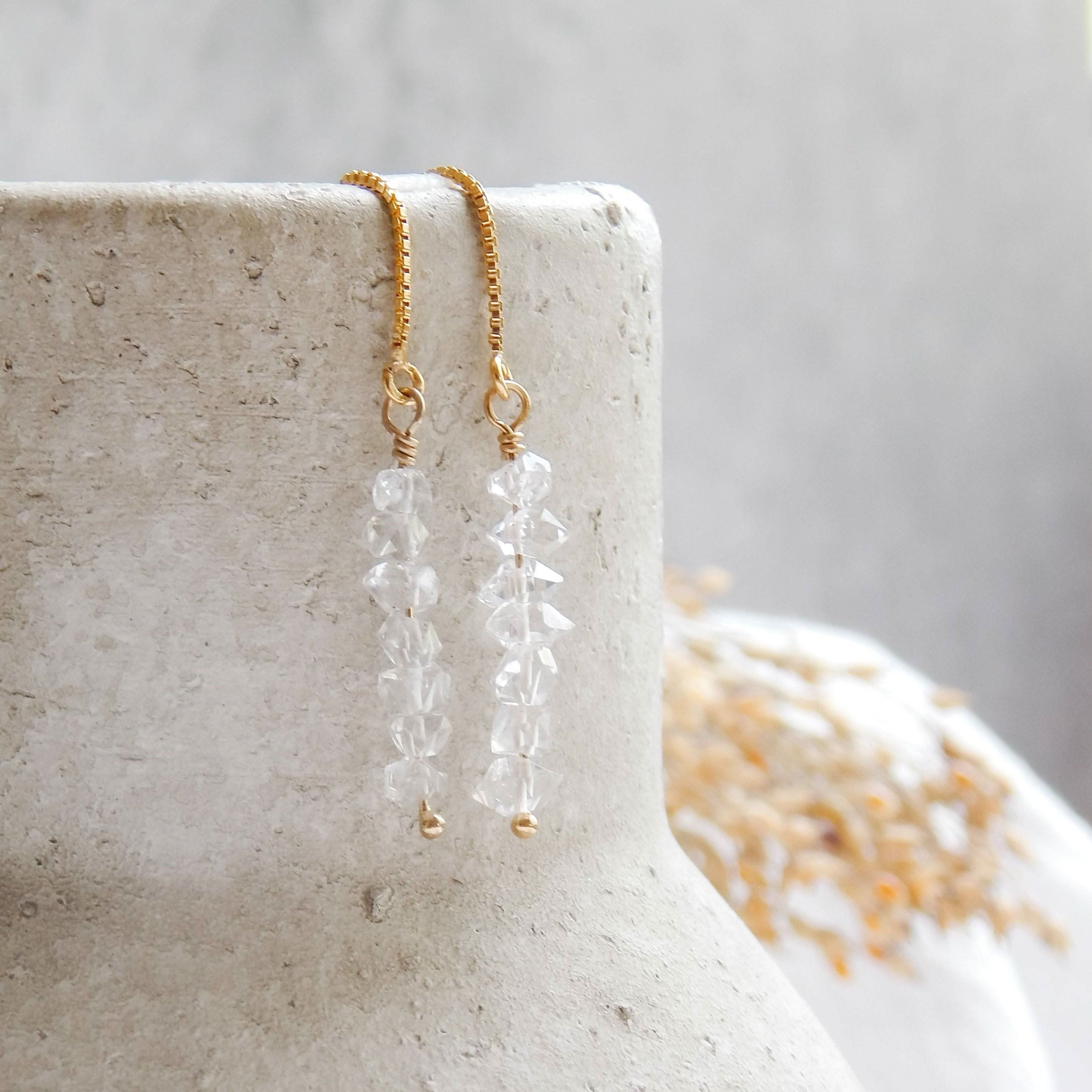 Herkimer Diamond Threaded Earrings by Barberry & Lace Jewelry displayed on a stone vase. Features 14k gold fill chain and raw crystal stones.