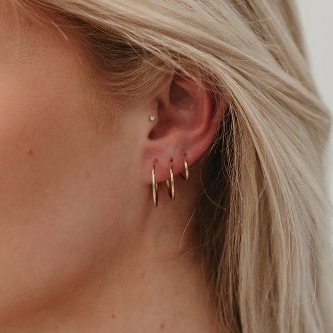Model wearing multiple Endless Huggie Hoop Earrings in gold fill, showcasing their snug fit and elegant everyday style.