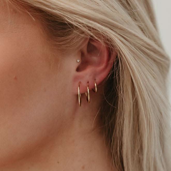 Model wearing multiple Endless Huggie Hoop Earrings in gold fill, showcasing their snug fit and elegant everyday style.