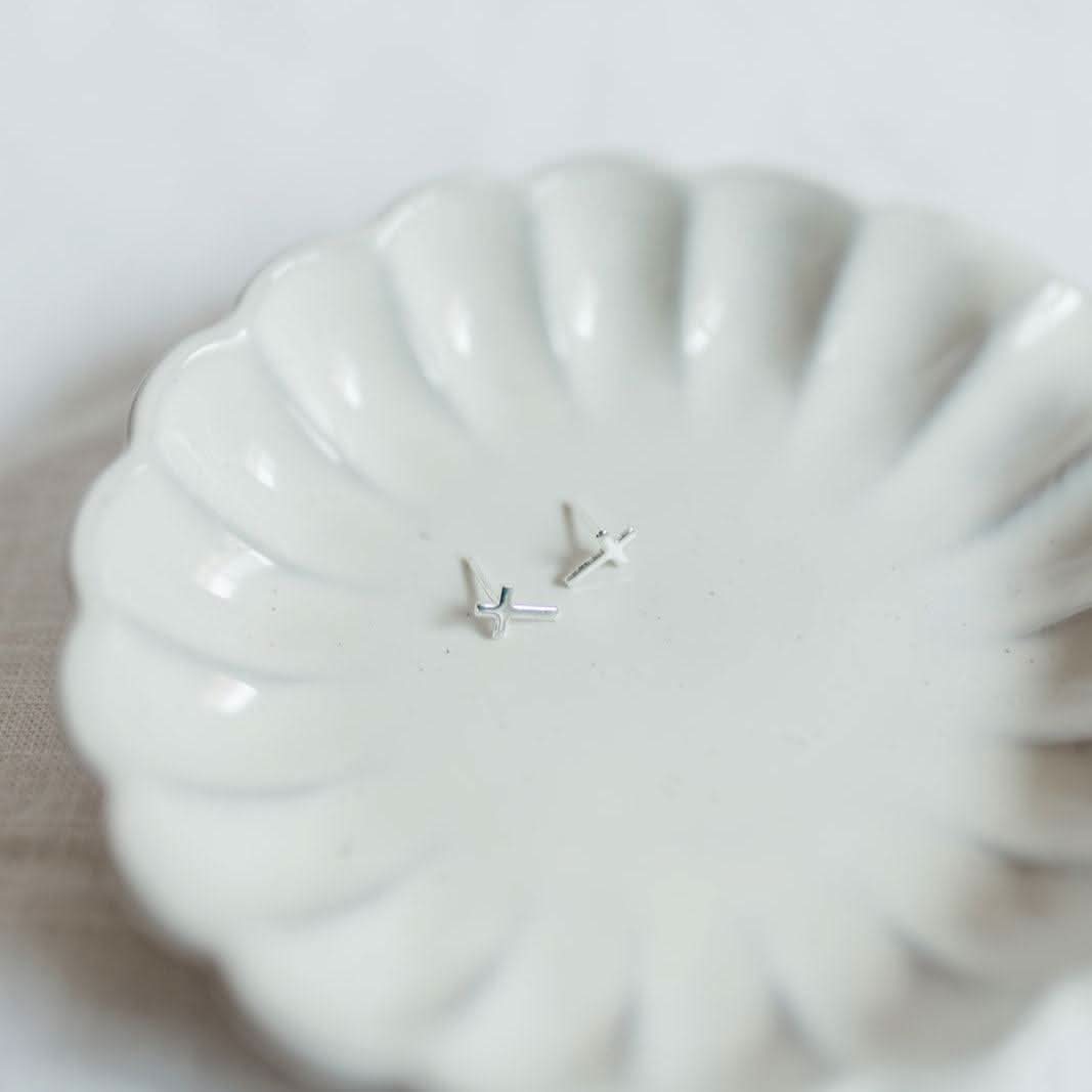 Hypoallergenic Cross Stud Earrings by Barberry & Lace Jewelry, sterling silver design displayed on a scalloped white ceramic dish.