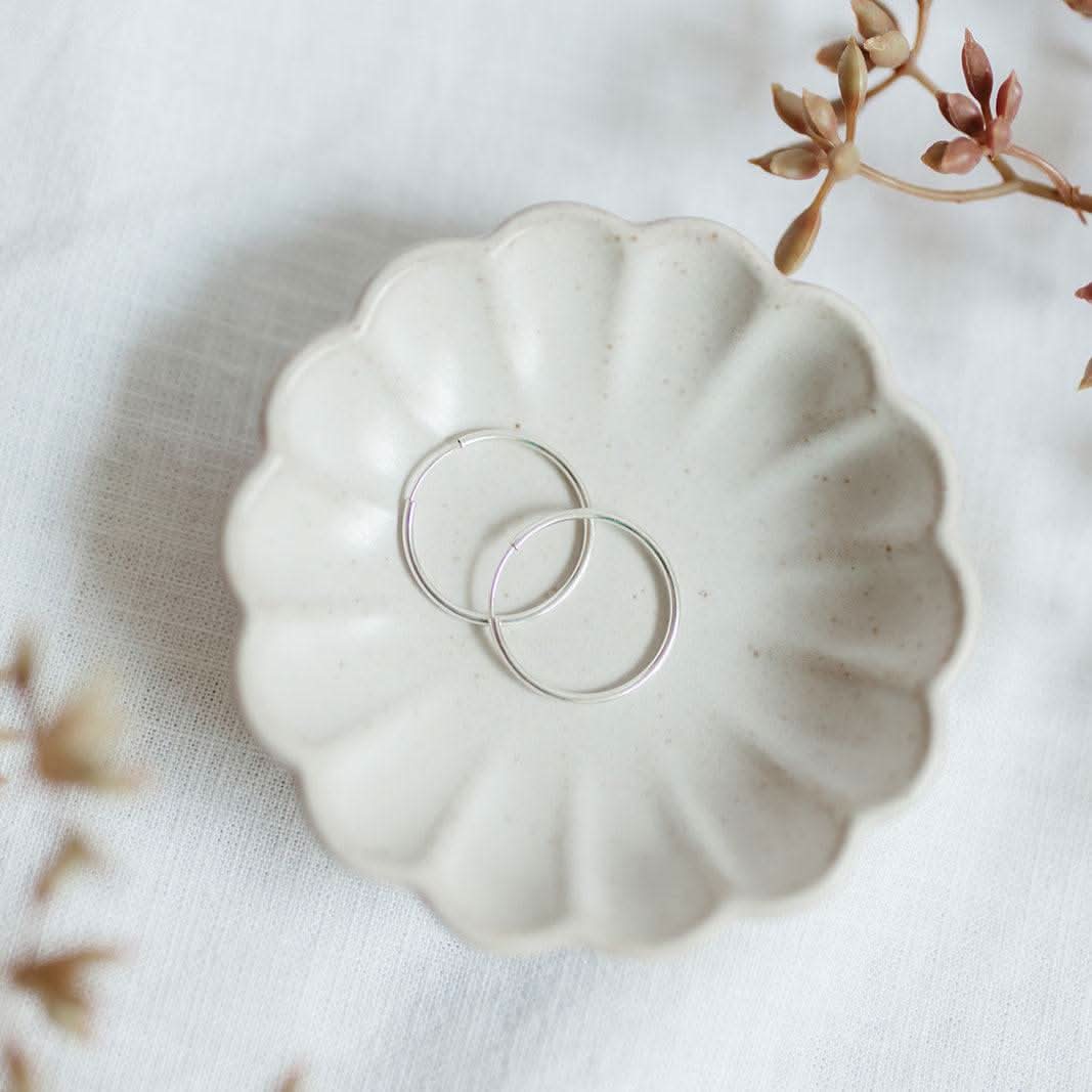 Large Endless Huggie Hoop Earrings in sterling silver displayed in a ceramic dish, ideal for a bold yet classic jewelry statement.