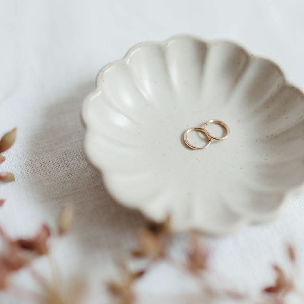 Small Endless Huggie Hoop Earrings in gold fill placed in a scalloped ceramic dish, perfect for minimalist jewelry lovers.