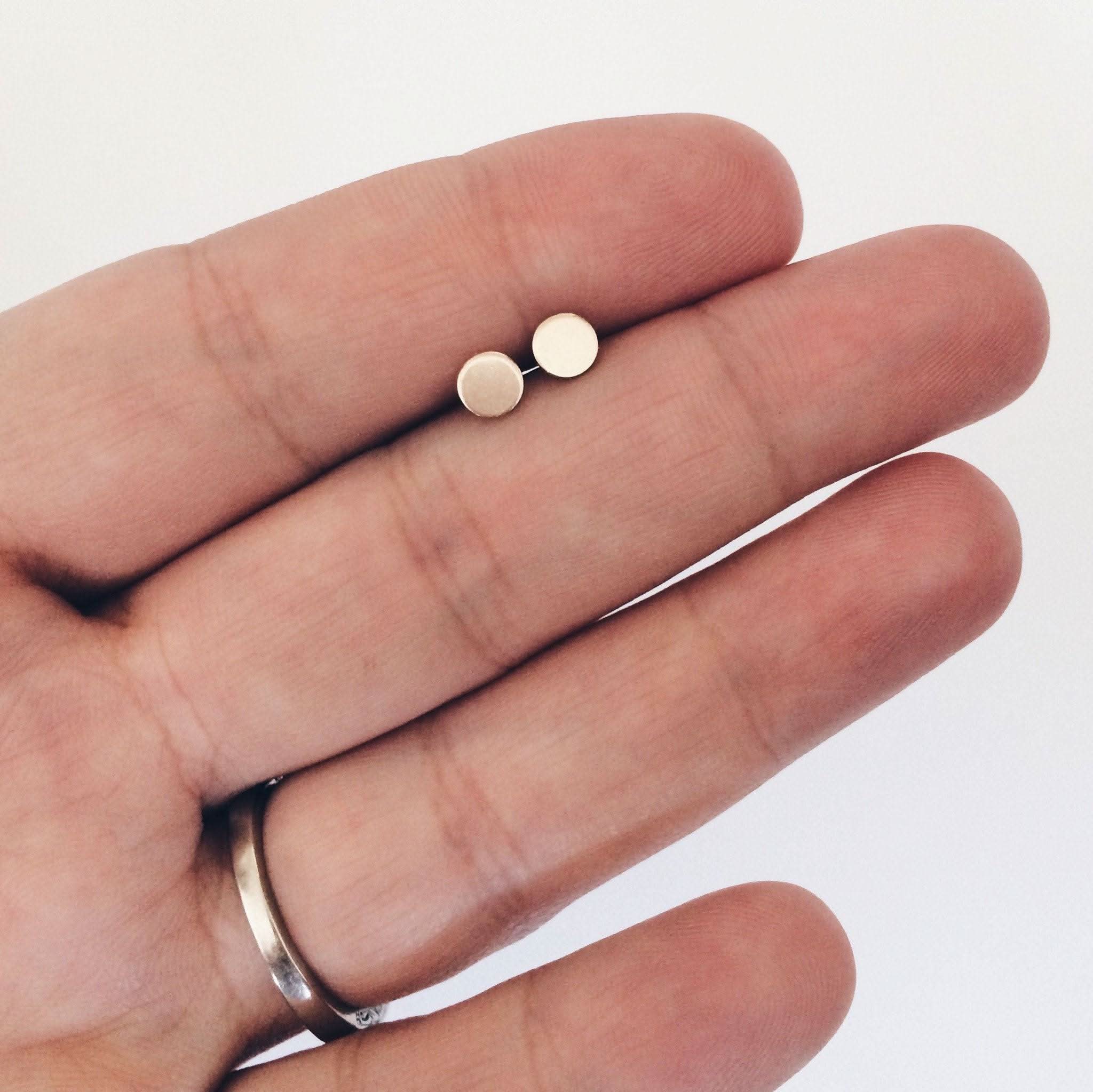 Close-up of Tiny Dot Stud Earrings in hand, showcasing their small size and delicate design for subtle, everyday sparkle.