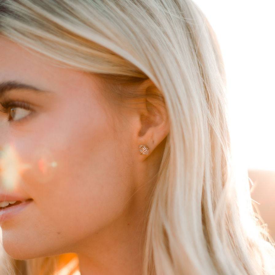 Barberry & Lace Herkimer Diamond Stud Earrings worn by a blonde model in soft sunlight, emphasizing the crystal clarity and gold wrap detail.