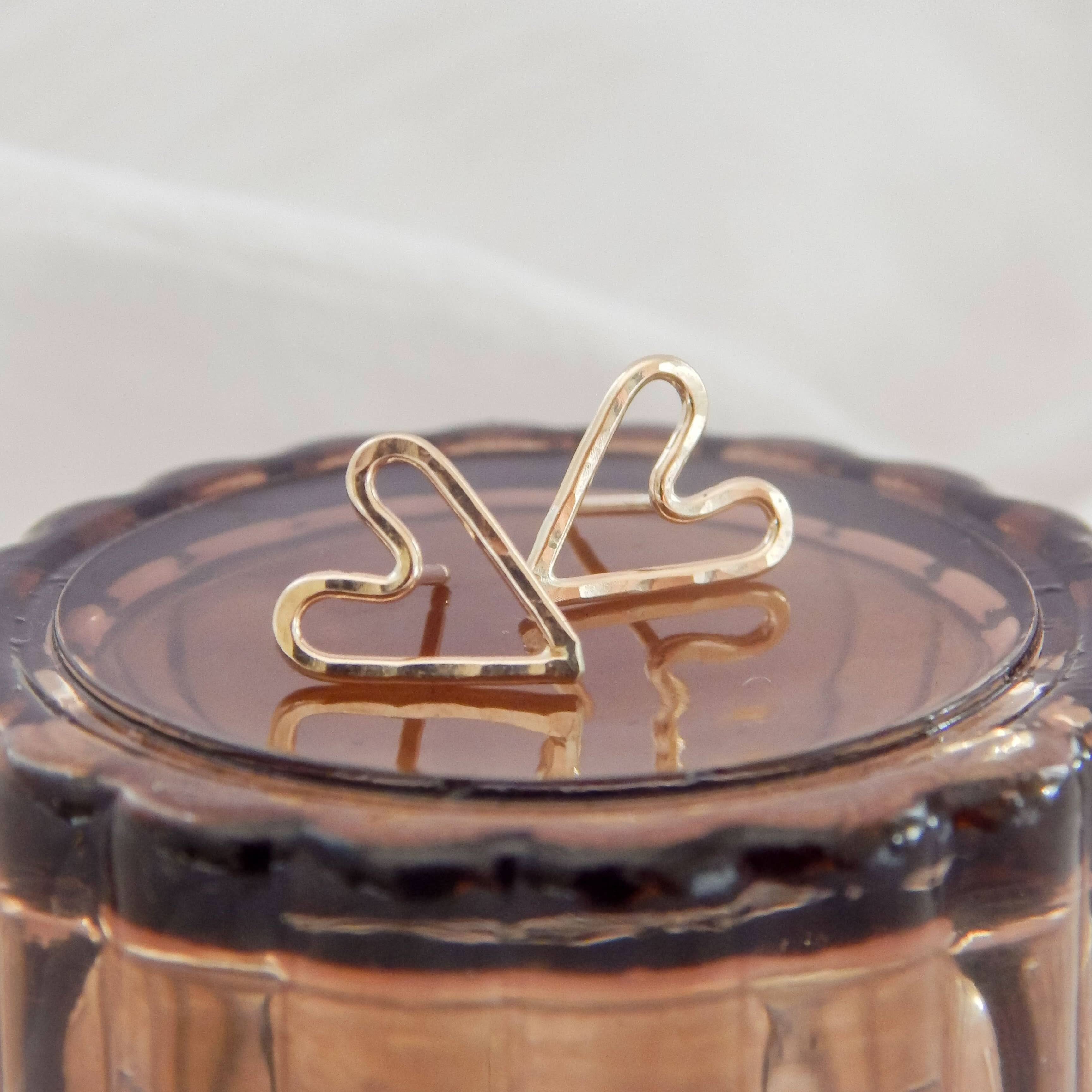 Close-up of Hammered Heart Stud Earrings resting on a glass surface, emphasizing the hammered texture and elegant heart outline.