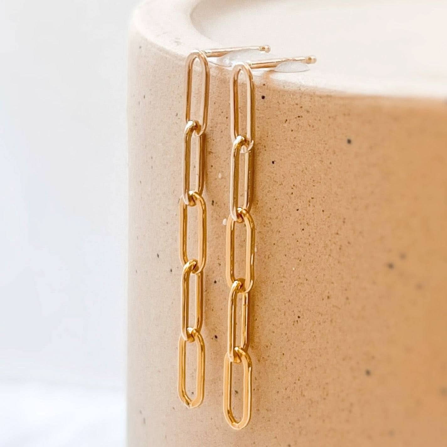 Pair of Barberry & Lace Paperclip Stud Earrings in 14k Gold Fill resting on ceramic surface, highlighting sleek, waterproof chain-link design.