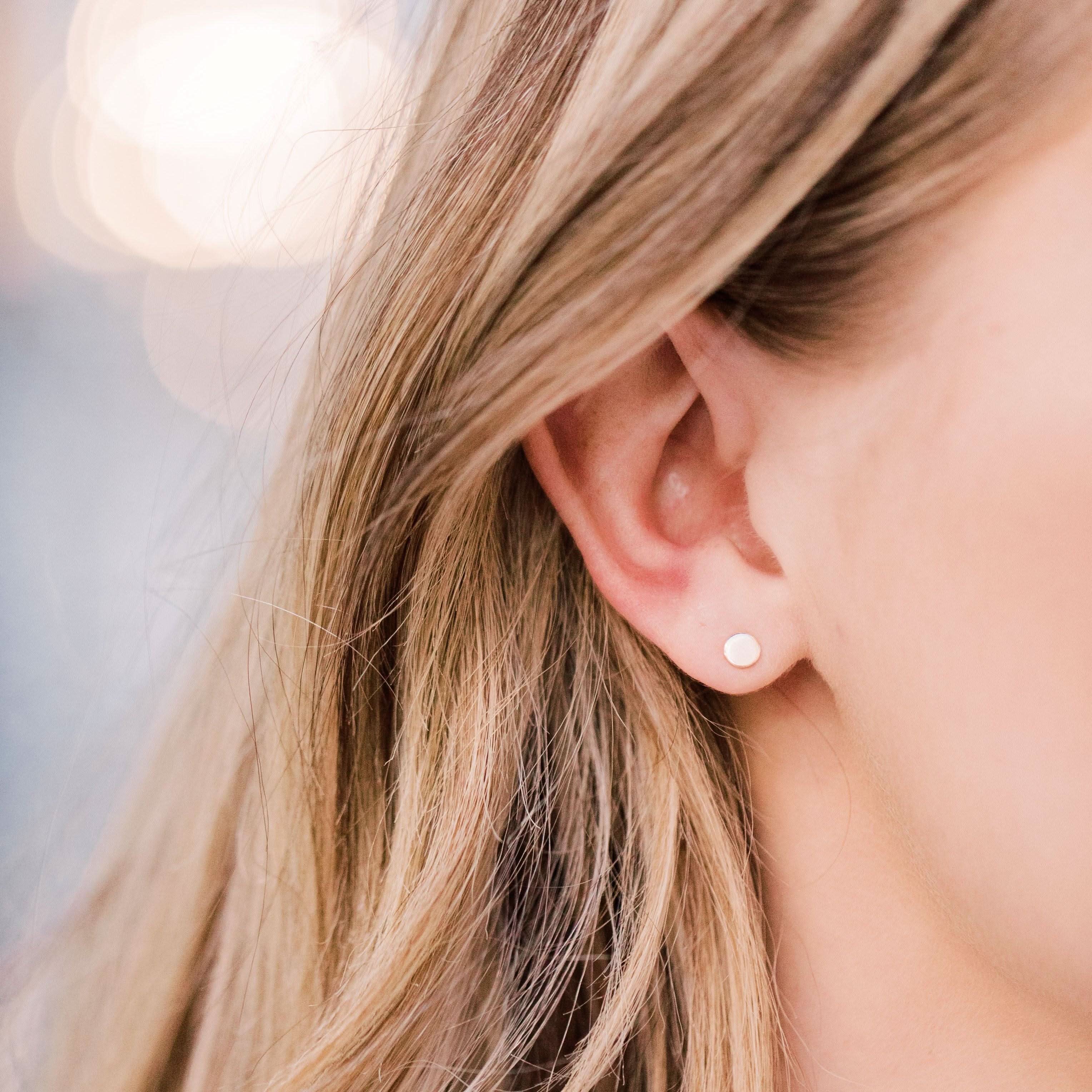 Tiny Dot Circle Stud Earrings worn on ear, highlighting their minimalist style and hypoallergenic finish for daily use.