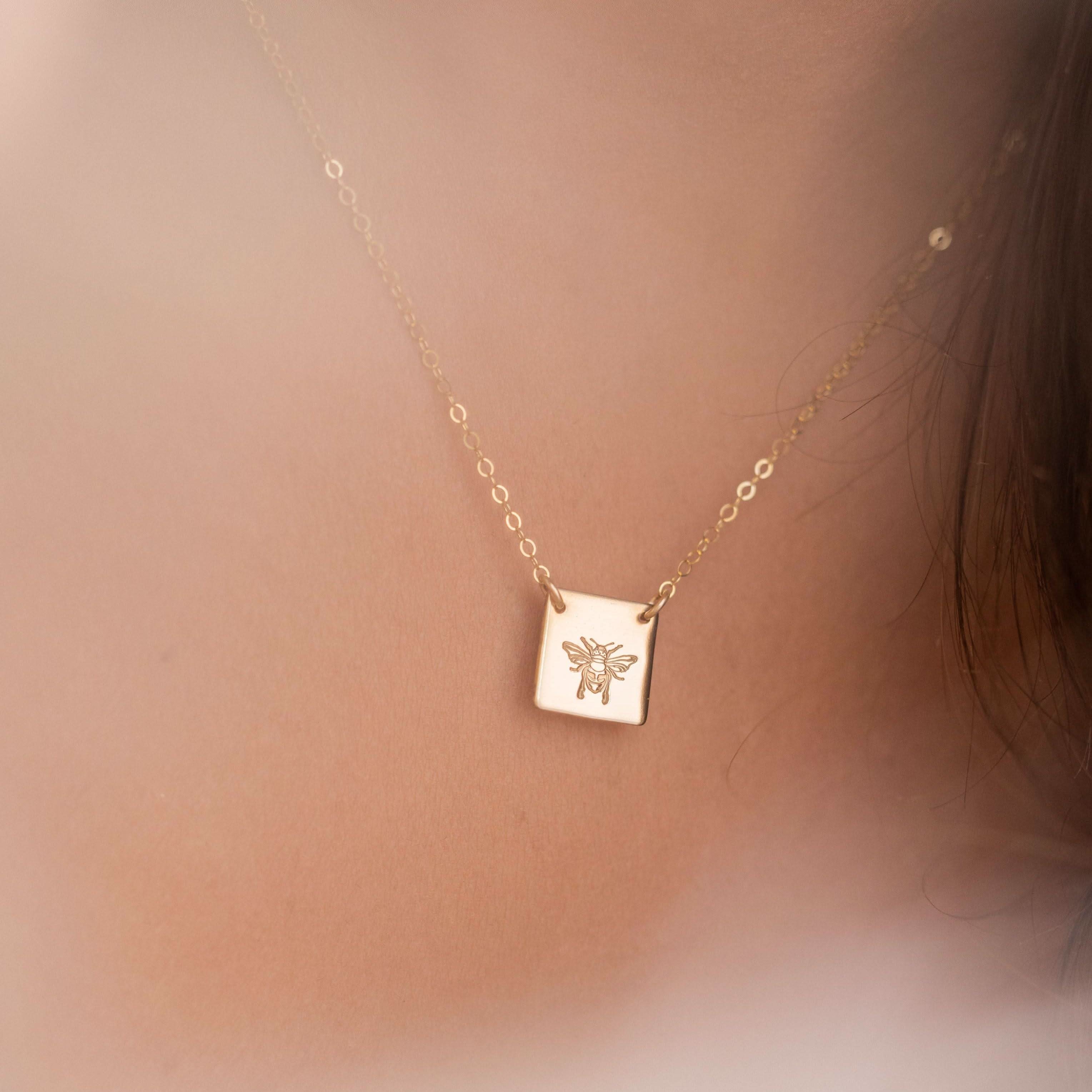 Close-up of Honey Bee Necklace worn on neck, showcasing the engraved bee pendant in 14k gold fill. A charming and hypoallergenic accessory.