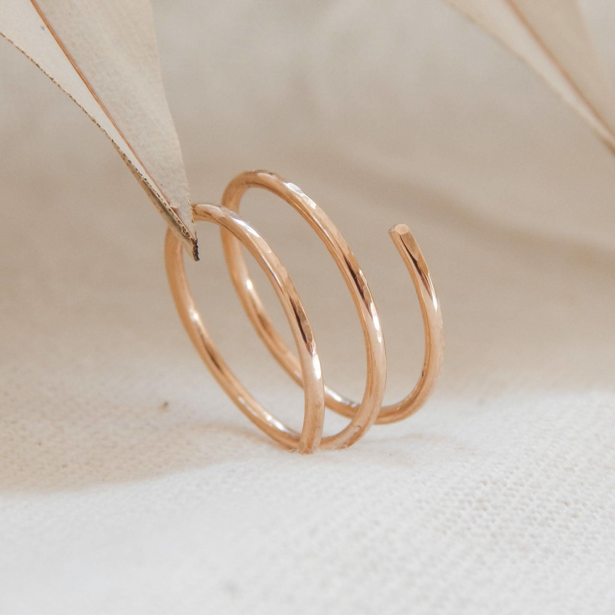 Waterproof Hammered Wrap Ring in 14k Gold Fill with a minimalist spiral design, displayed on a neutral fabric background.