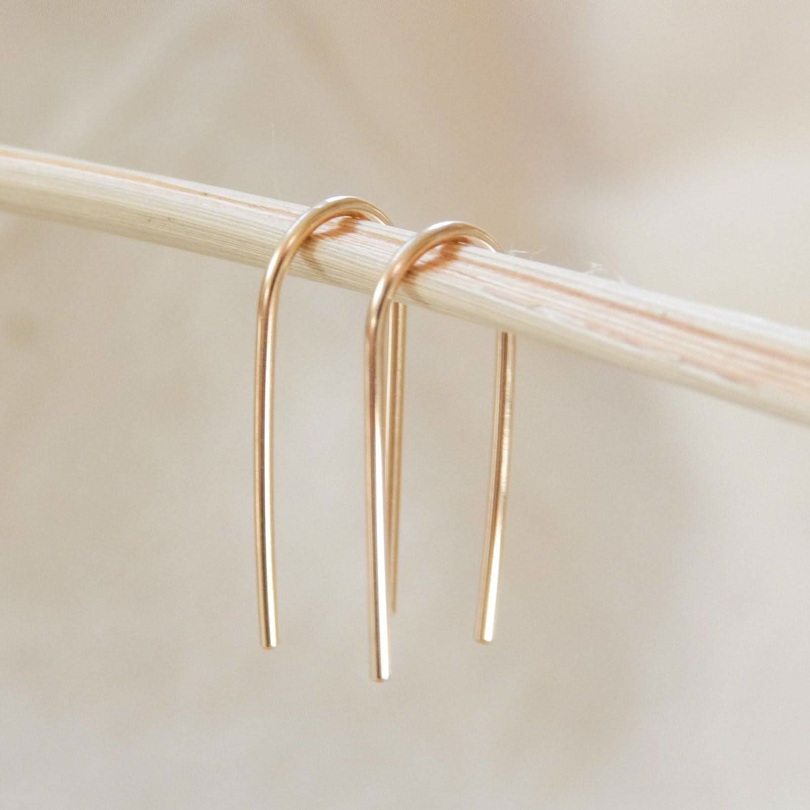Minimalist Open Arc Earrings in 14k Gold Fill hanging on a neutral branch, showcasing their sleek and modern curved design.