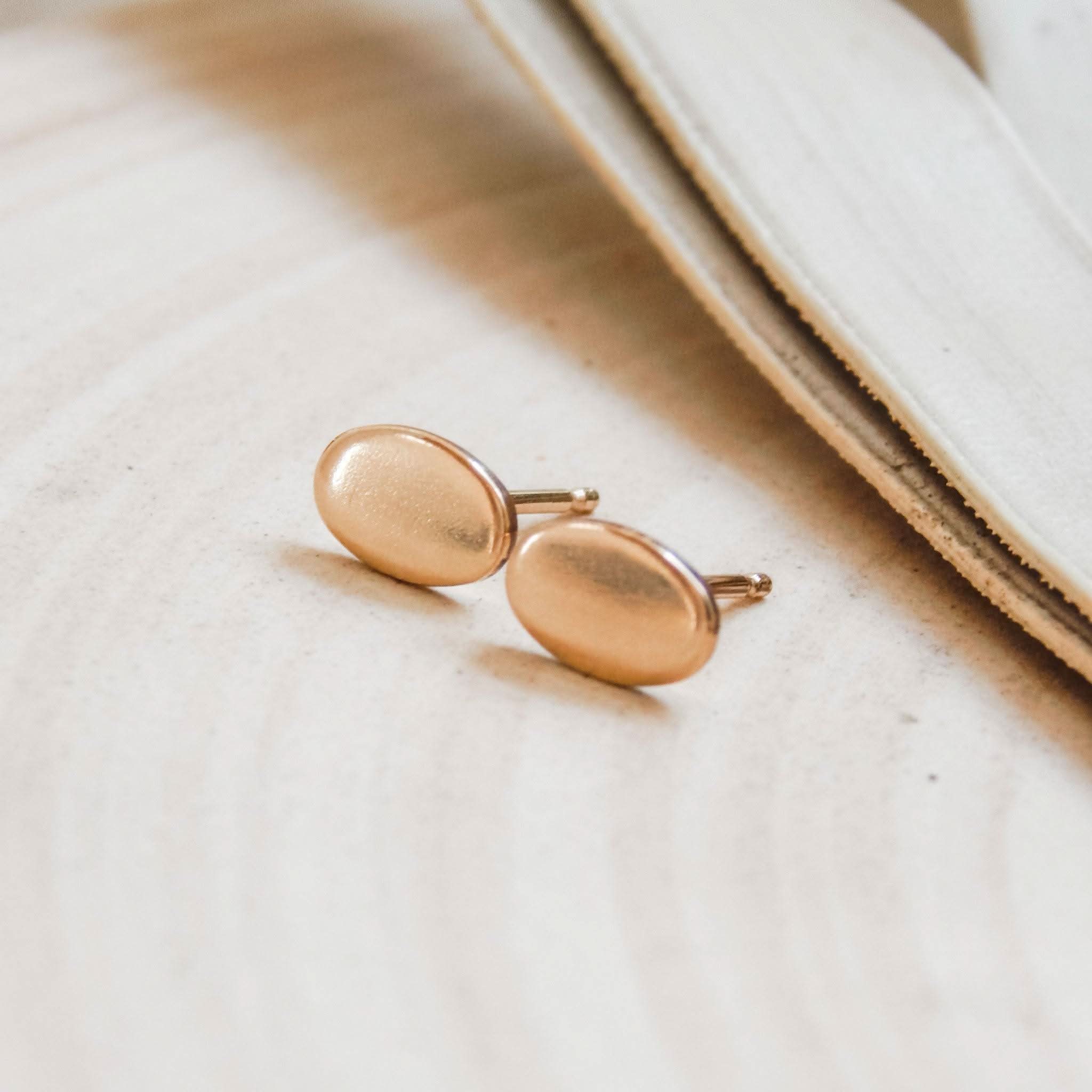Pair of Barberry & Lace Hypoallergenic Oval Stud Earrings in 14k Gold Fill resting on a soft beige surface.