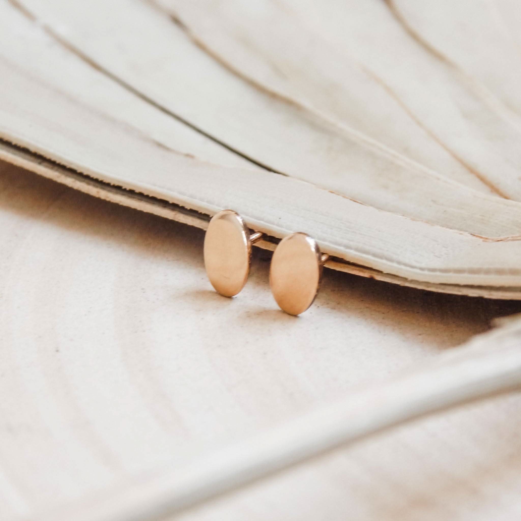 Close-up of Barberry & Lace Hypoallergenic Oval Stud Earrings in 14k Gold Fill, displayed on neutral-toned dried leaves.