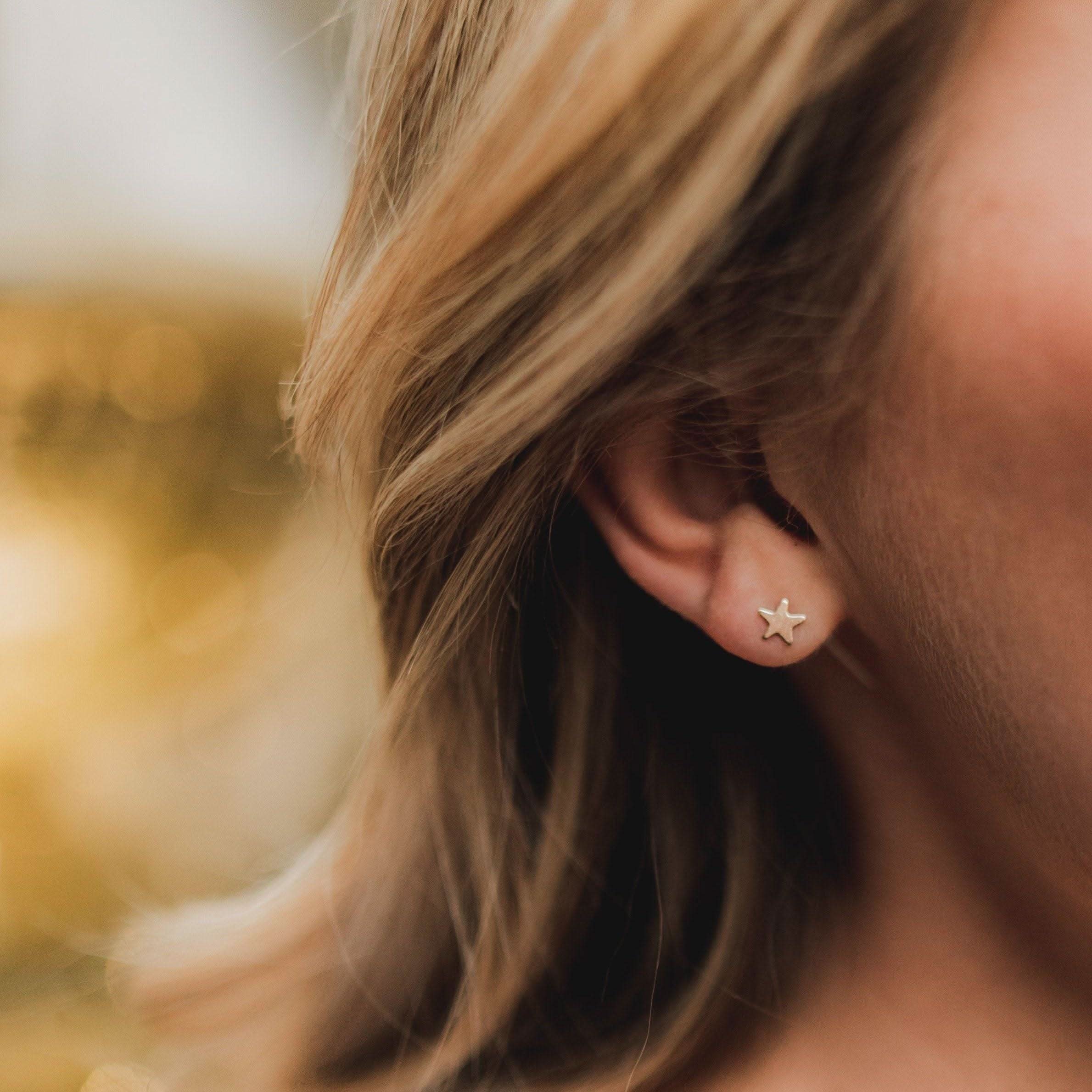 Close-up of Hypoallergenic Star Stud Earrings worn on ear, showcasing minimalist gold star design ideal for sensitive skin.
