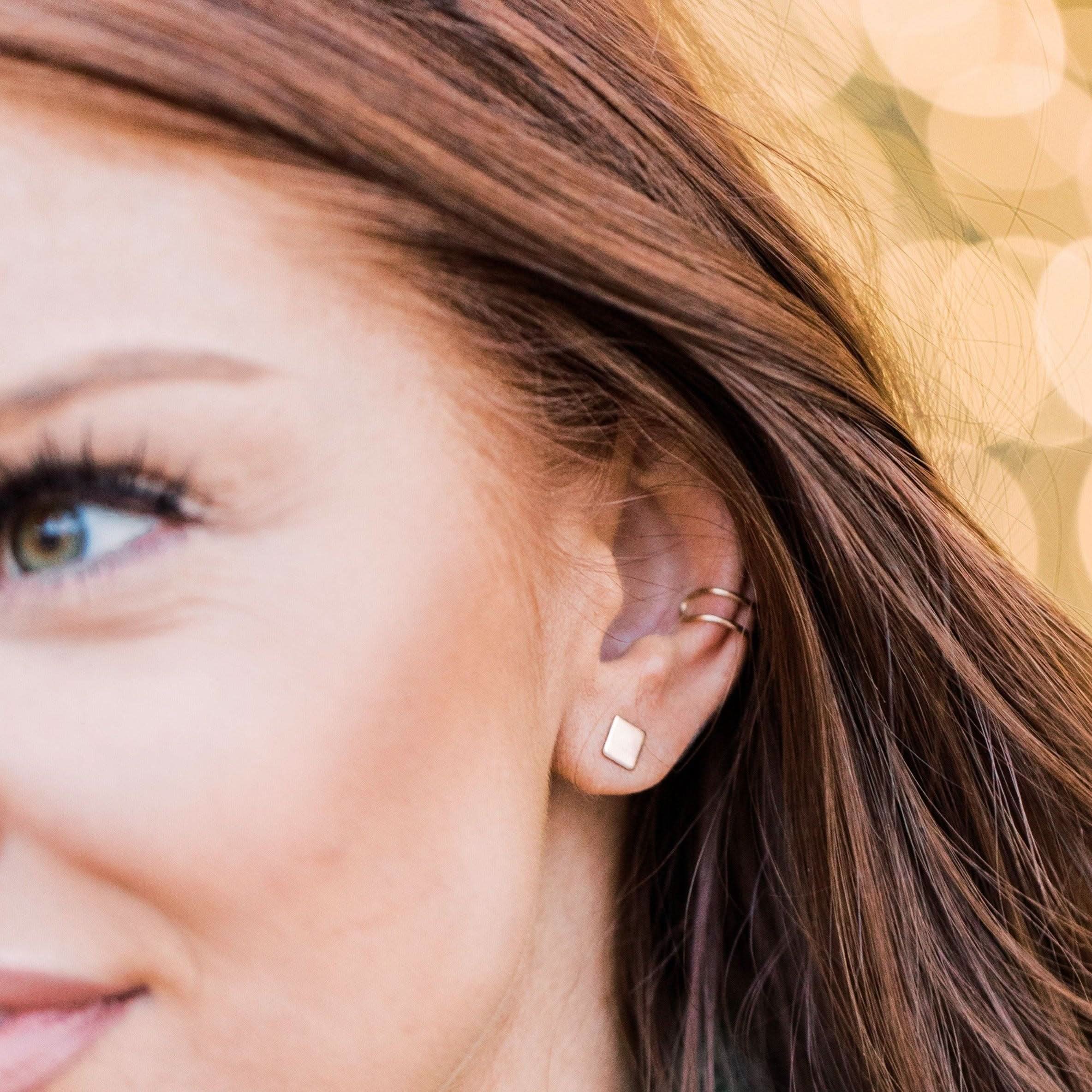Model showcasing double band no-pierce ear cuff earring in gold, styled with square stud for a modern ear stack.