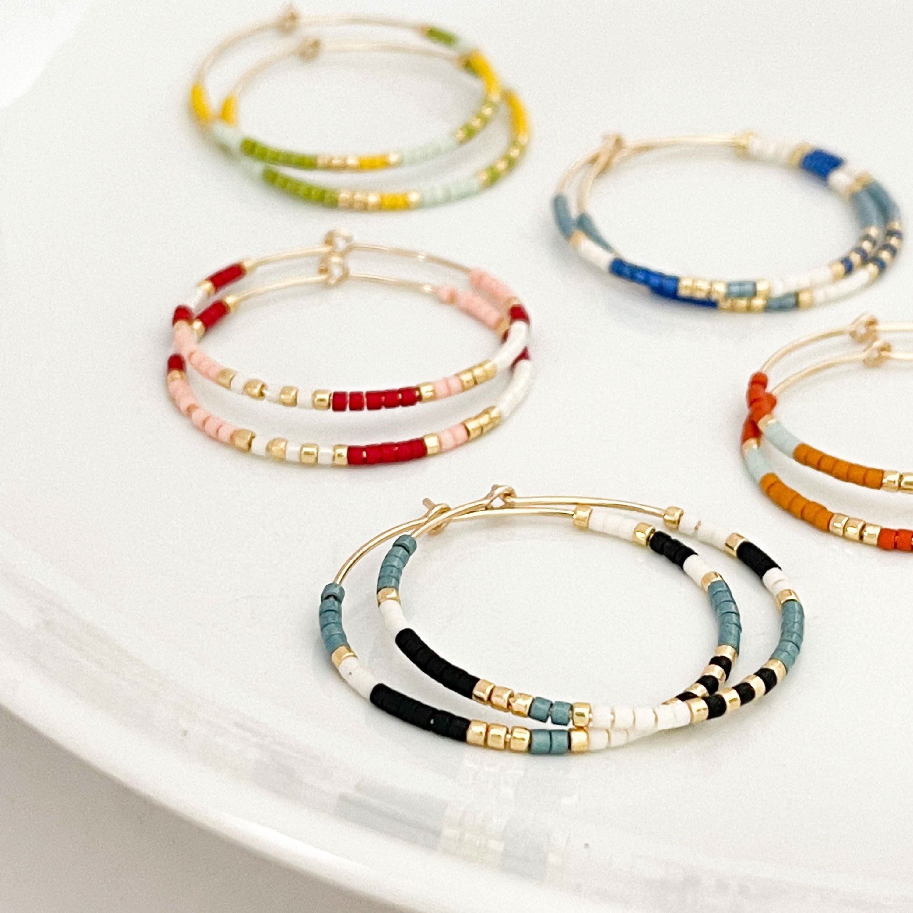 Summer Edition - Beaded Hoop Earrings in assorted boho colorways on a white plate, featuring gold hoops with colorful seed beads.