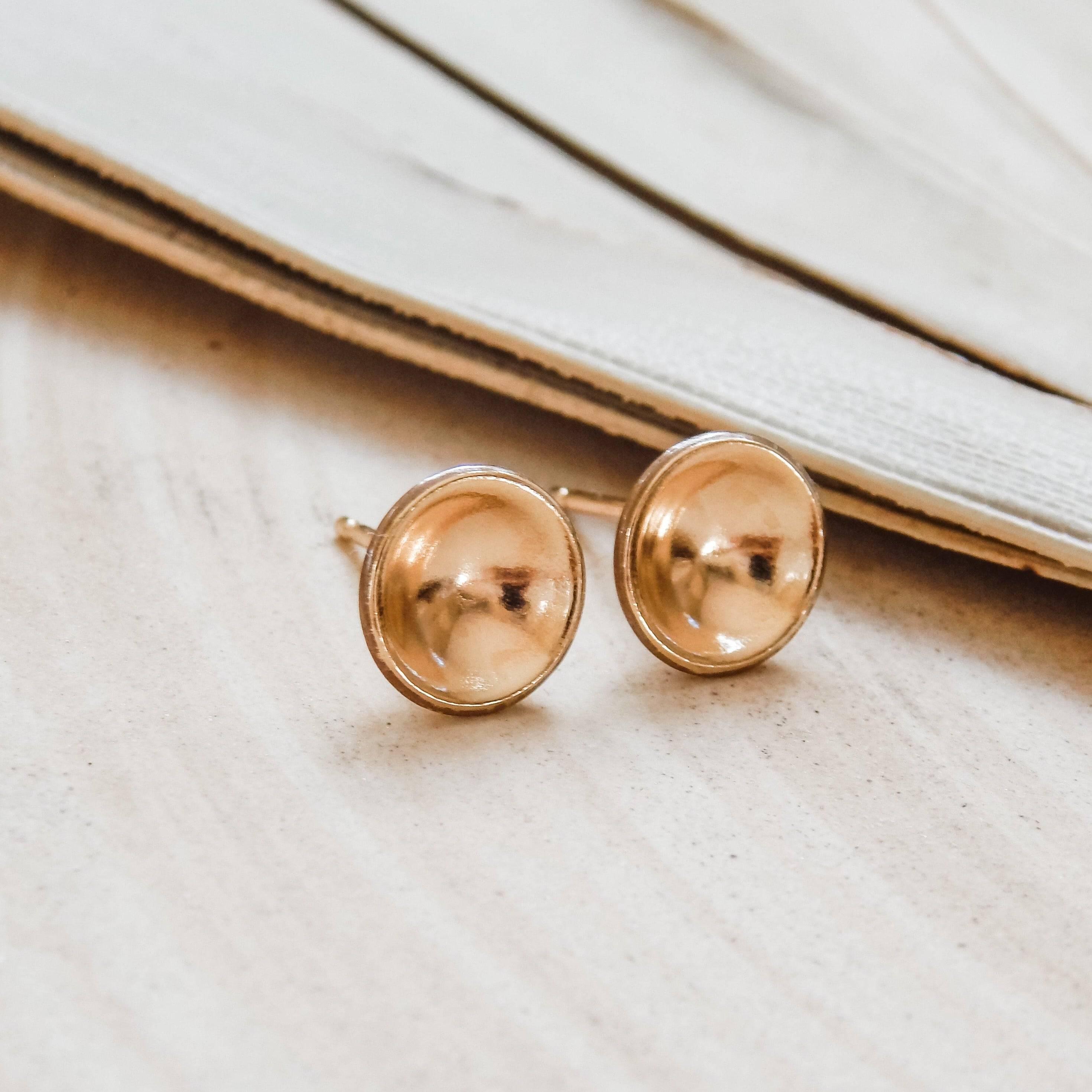 Pair of Concave Disc Stud Earrings in 14k Gold Fill displayed on neutral surface, highlighting their polished, domed shape.