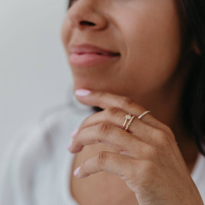 Woman smiling while wearing Baguette Twisted Stacking Ring on her finger, showcasing its dainty and hypoallergenic design.