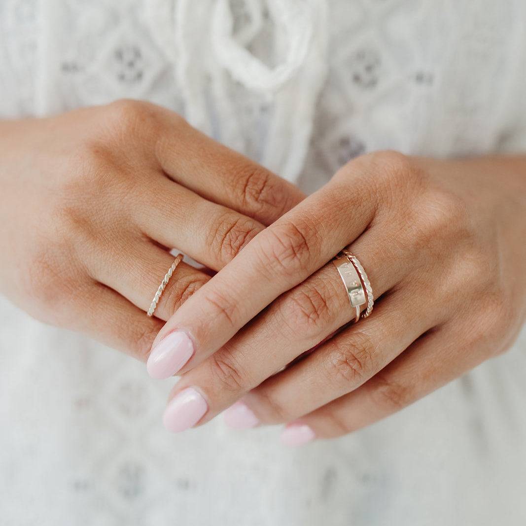 Woman wearing the Mama Bar Ring stacked with other delicate rings, showcasing its elegant and dainty design for everyday wear.