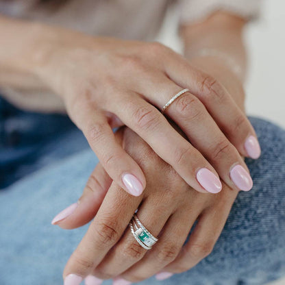 Close-up of hands wearing Baguette Twisted Stacking Rings in mixed metals, styled for a layered and modern jewelry look.