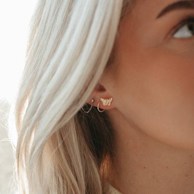 Model wearing Butterfly Stud Earrings in 14k Gold Fill by Barberry & Lace Jewelry, showcasing dainty and elegant ear styling.