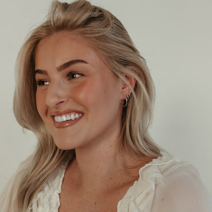 Smiling model wearing Endless Huggie Hoop Earrings in gold fill, highlighting their lightweight and versatile everyday appeal.
