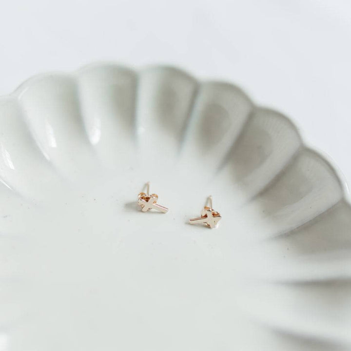 Hypoallergenic Cross Stud Earrings by Barberry & Lace Jewelry, delicate gold design on a white scalloped dish, perfect for sensitive ears.