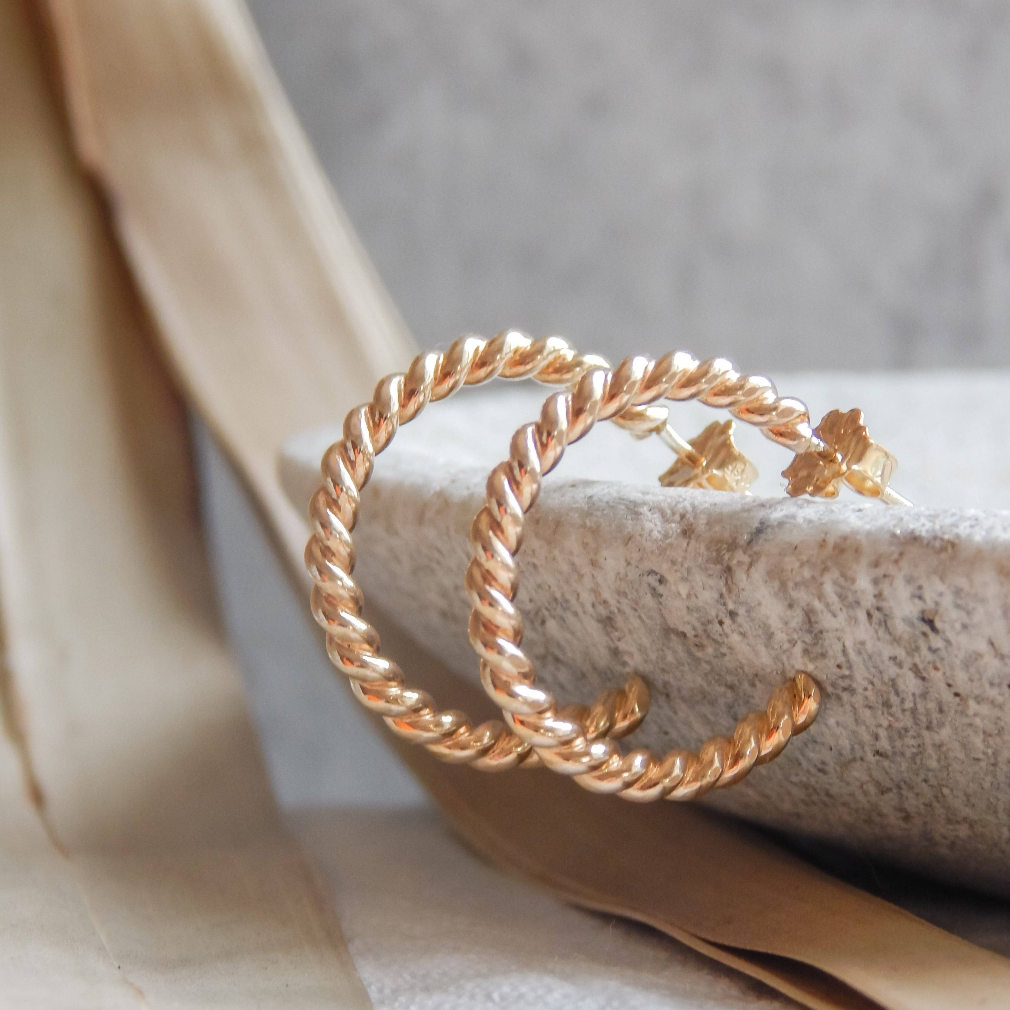 Twist Hoop Earrings by Barberry & Lace Jewelry featuring a gold twisted design, hypoallergenic and waterproof, displayed on a neutral stone surface.