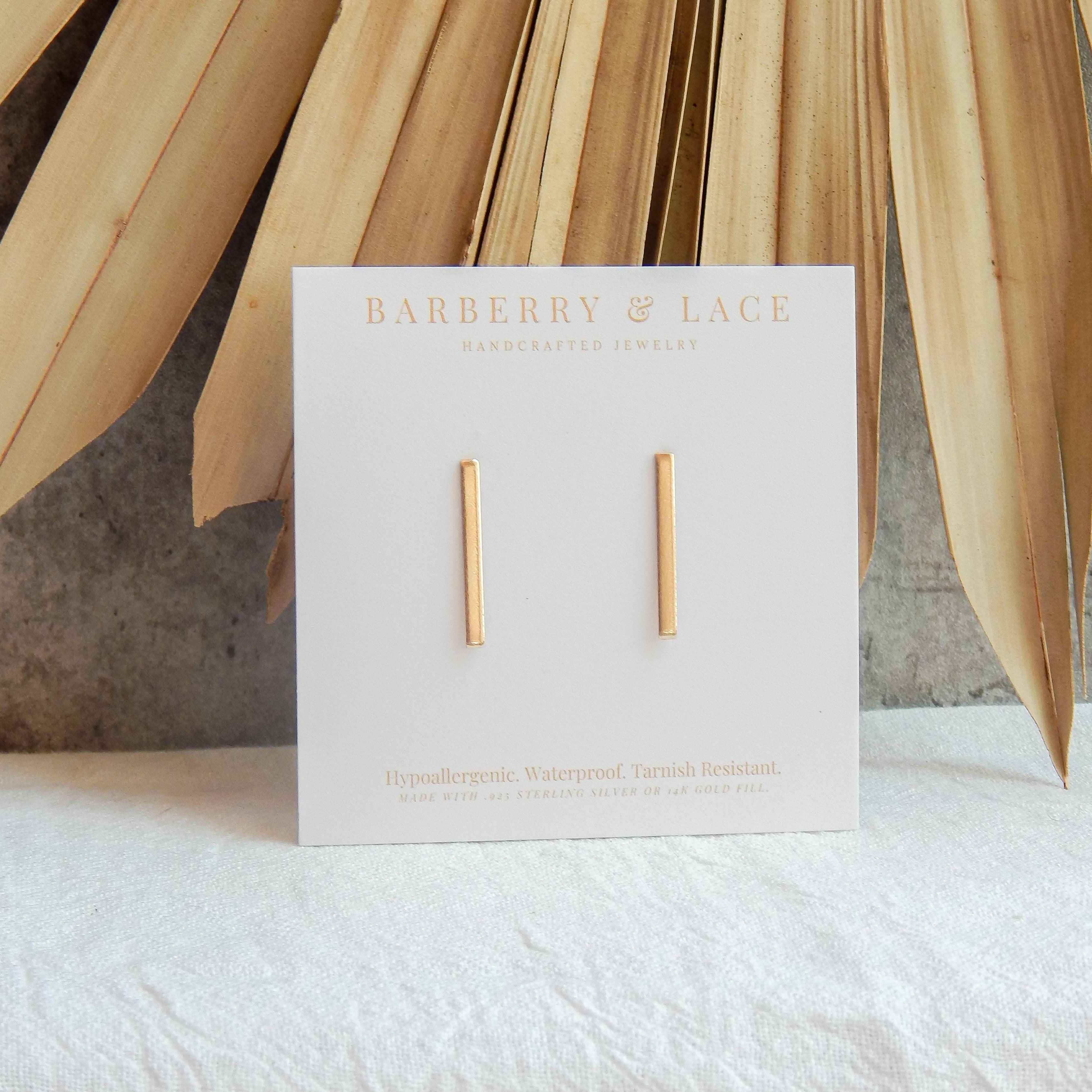 Stick Stud Earrings by Barberry & Lace Jewelry displayed on branded card. Minimalist 14k gold fill design, hypoallergenic and waterproof.