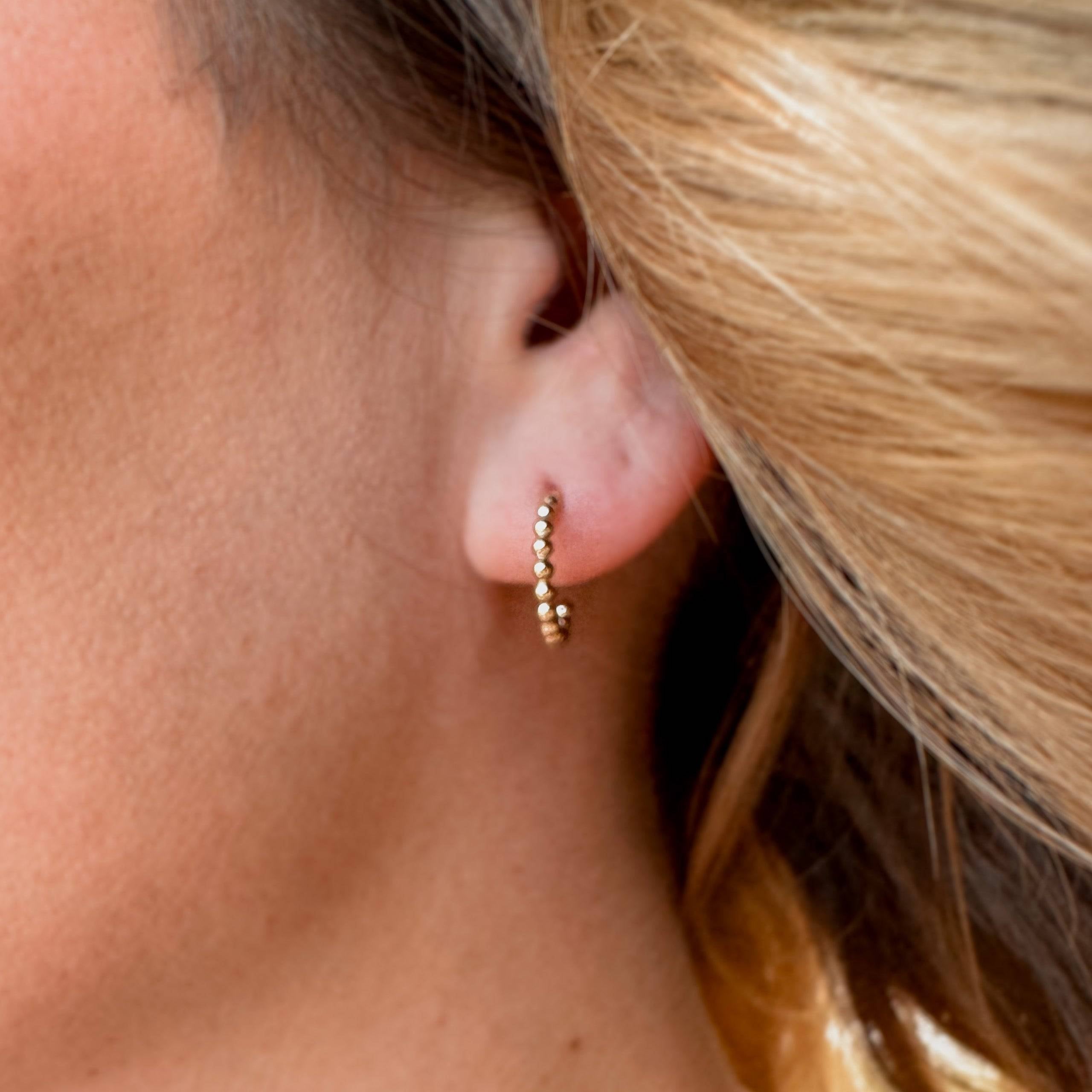 Close-up of Beaded Huggie Hoop Earrings worn on ear. Chic 14k gold fill design perfect for hypoallergenic, minimalist style.