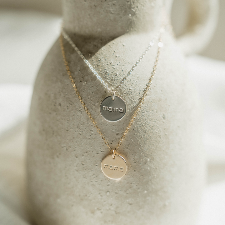 Gold and silver Mama Disc Necklaces by Barberry & Lace Jewelry displayed on a ceramic vase, highlighting hypoallergenic and waterproof options.