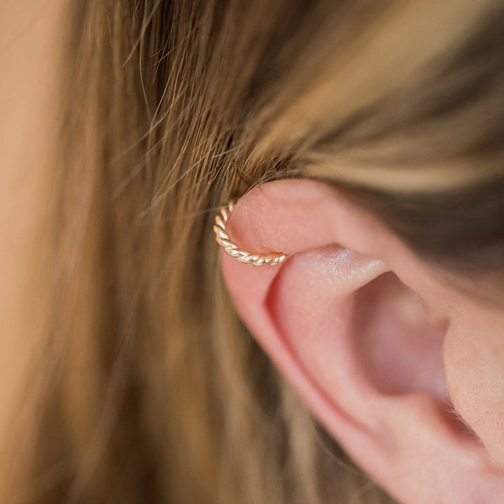 Gold twisted no-pierce ear cuff earring worn on upper ear, showcasing minimalist design from Barberry & Lace Jewelry.