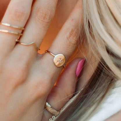 Woman wearing a Personalized Circle Stacking Ring by Barberry & Lace Jewelry with an engraved 'M', crafted in 14k gold fill, hypoallergenic design.