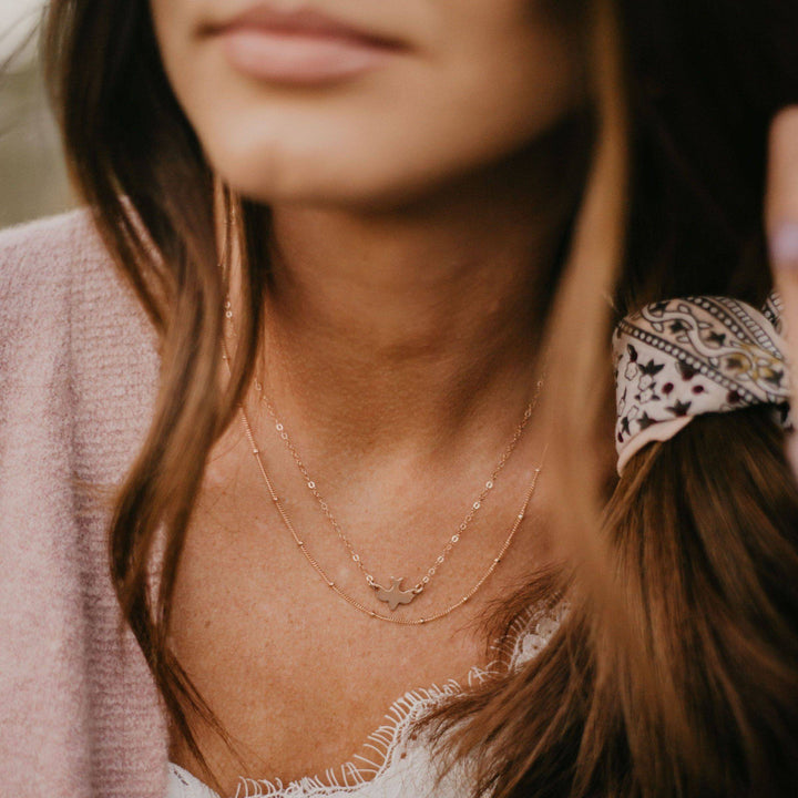 Model wearing Layering Satellite Chain Necklace in gold, paired with other dainty chains for a chic, minimalist jewelry look by Barberry & Lace.