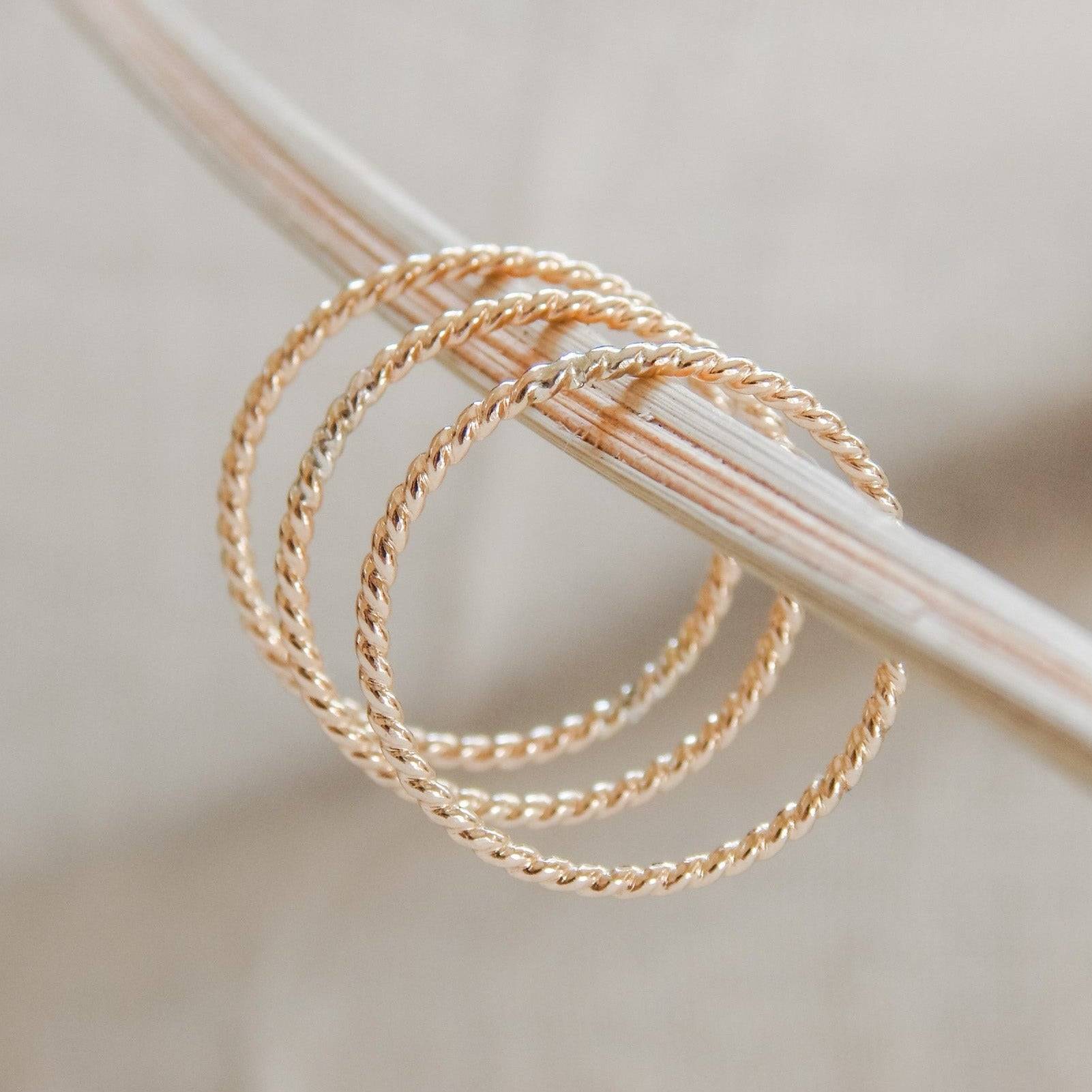 Petite Twisted Stacking Ring in 14k Gold Fill displayed in a trio on a neutral rod. Dainty and textured for everyday layering.