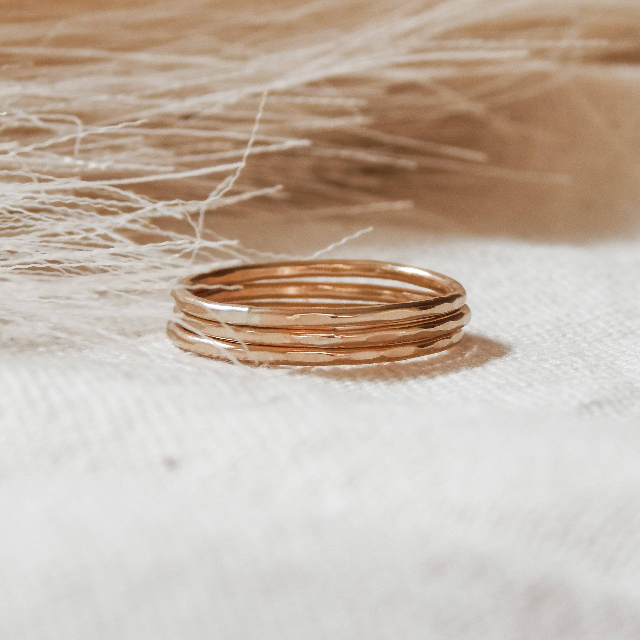 Set of Thin Hammered Band Stacking Rings in 14k gold fill resting on fabric, ideal for layering and everyday wear from Barberry & Lace Jewelry.