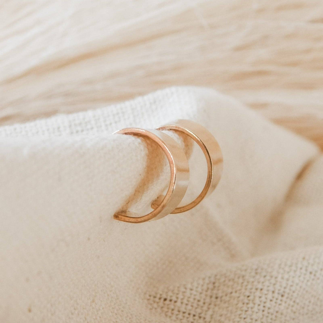 Pair of Thick Huggie Hoop Stud Earrings in gold fill on textured fabric, emphasizing their thick, curved shape and modern elegance.