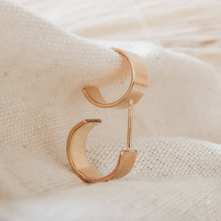 Thick Huggie Hoop Stud Earrings in 14k gold fill displayed on soft fabric, showcasing their bold, modern design and polished finish.