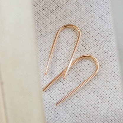 Pair of Minimalist Open Arc Earrings in 14k Gold Fill resting on textured fabric, emphasizing their handcrafted simplicity.