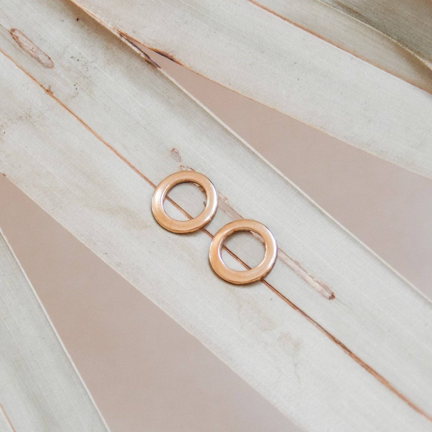 Minimalist Open Circle Stud Earrings in 14k Gold Fill by Barberry & Lace, displayed on a neutral palm leaf background for modern elegance.