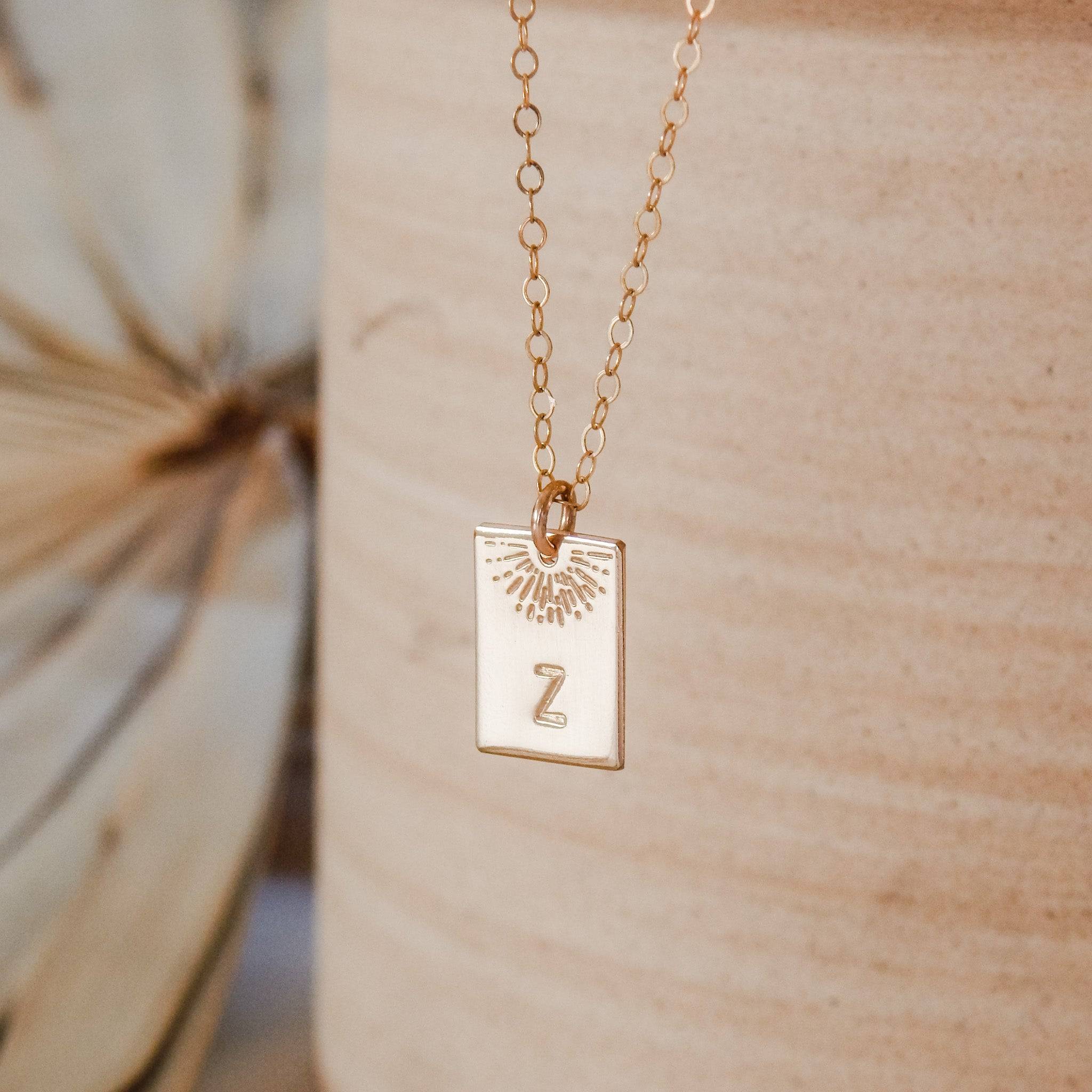 Hand Stamped Sunrise Initial Necklace by Barberry & Lace Jewelry featuring a gold filled rectangular pendant with sunrise design and letter Z.