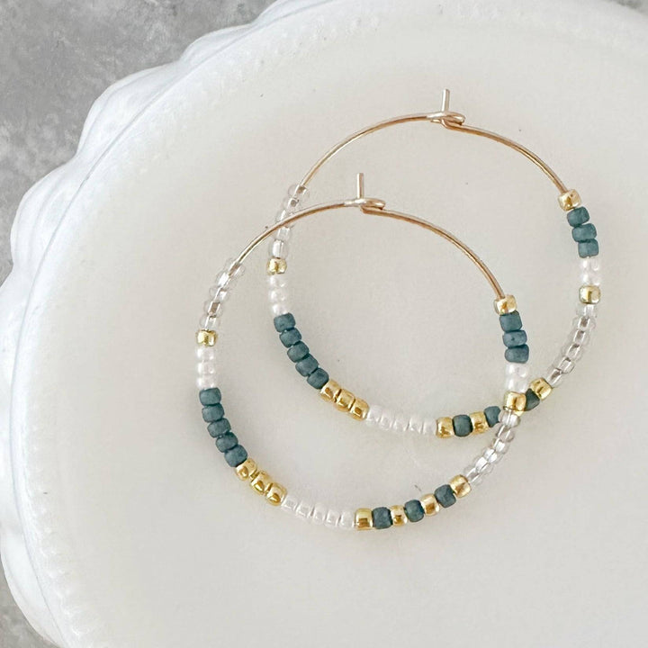 Holiday Edition - Beaded Hoop Earrings in Snowfall design with white, green, and gold beads on 14k gold fill hoops. Elegant and festive jewelry.