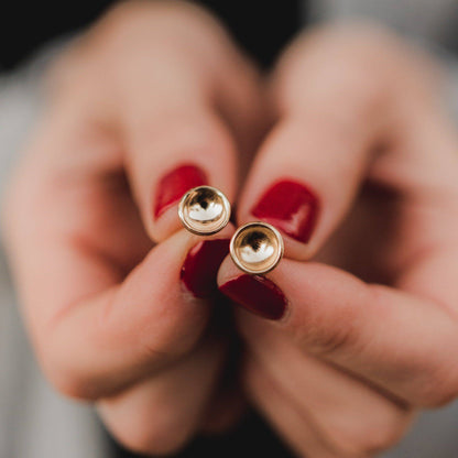 Concave Disc Stud Earrings in 14k Gold Fill held between fingers, emphasizing their shiny, handcrafted finish and minimalist style.