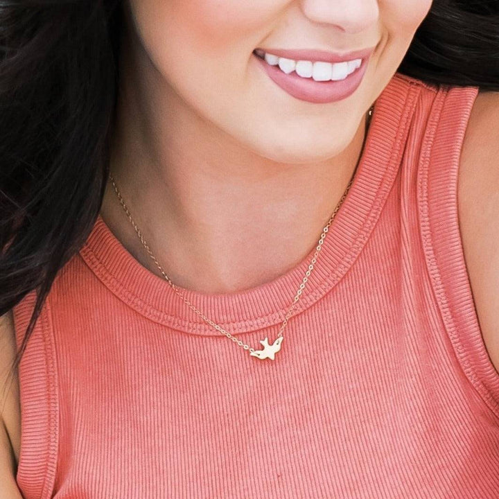 Model wearing the Layering Soaring Bird Necklace by Barberry & Lace, showcasing its dainty gold bird charm on a fine chain for everyday elegance.