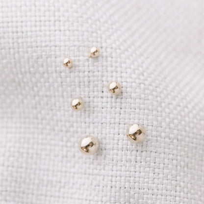 Assorted sizes of Ball Stud Earrings for Lobe & Cartilage in 14k Gold Fill displayed on white textured fabric. Waterproof and tarnish resistant.
