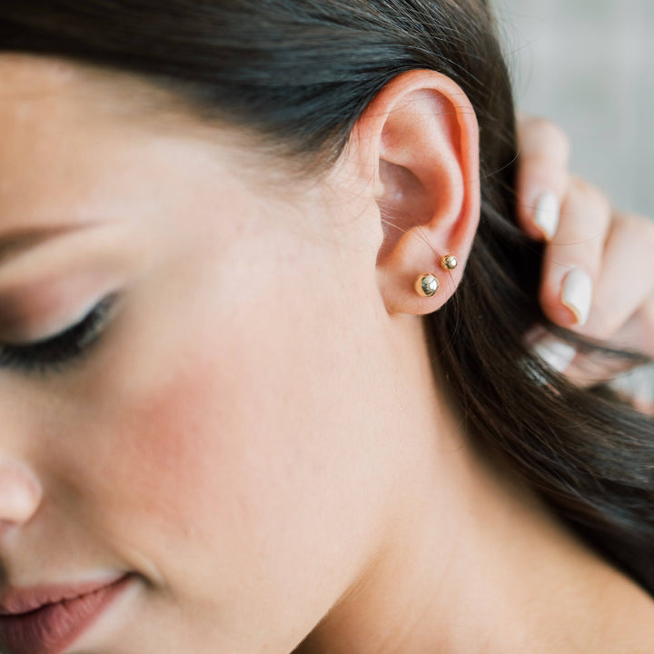Ball Stud Earrings for Lobe & Cartilage in 14k Gold Fill shown on model with double ear piercings. Minimalist and hypoallergenic design.