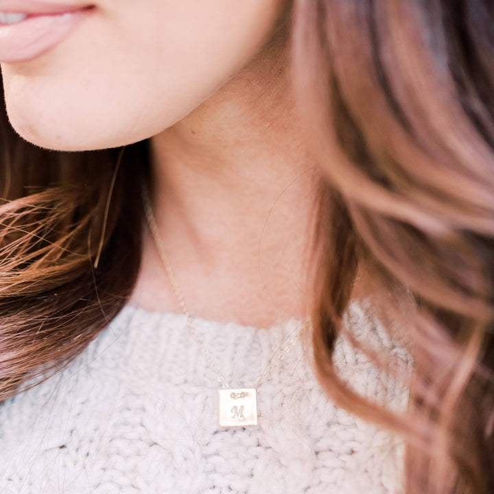 Personalized Square Necklace by Barberry & Lace Jewelry featuring a gold hand-stamped initial pendant on a delicate chain, worn with a knit sweater.