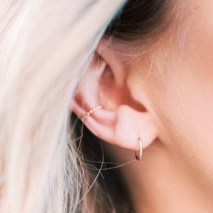 Model wearing beaded and smooth no-pierce ear cuff earrings in gold, highlighting a trendy layered ear style.