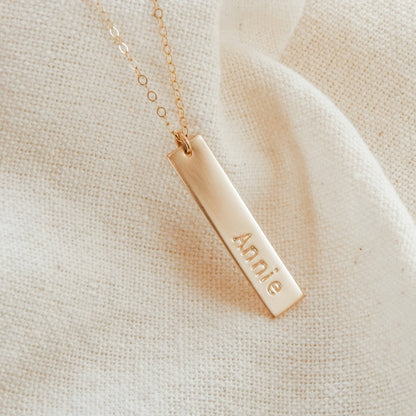 Personalized Vertical Bar Necklace by Barberry & Lace Jewelry featuring a gold bar engraved with 'Annie' on a delicate chain, ideal for gifting.