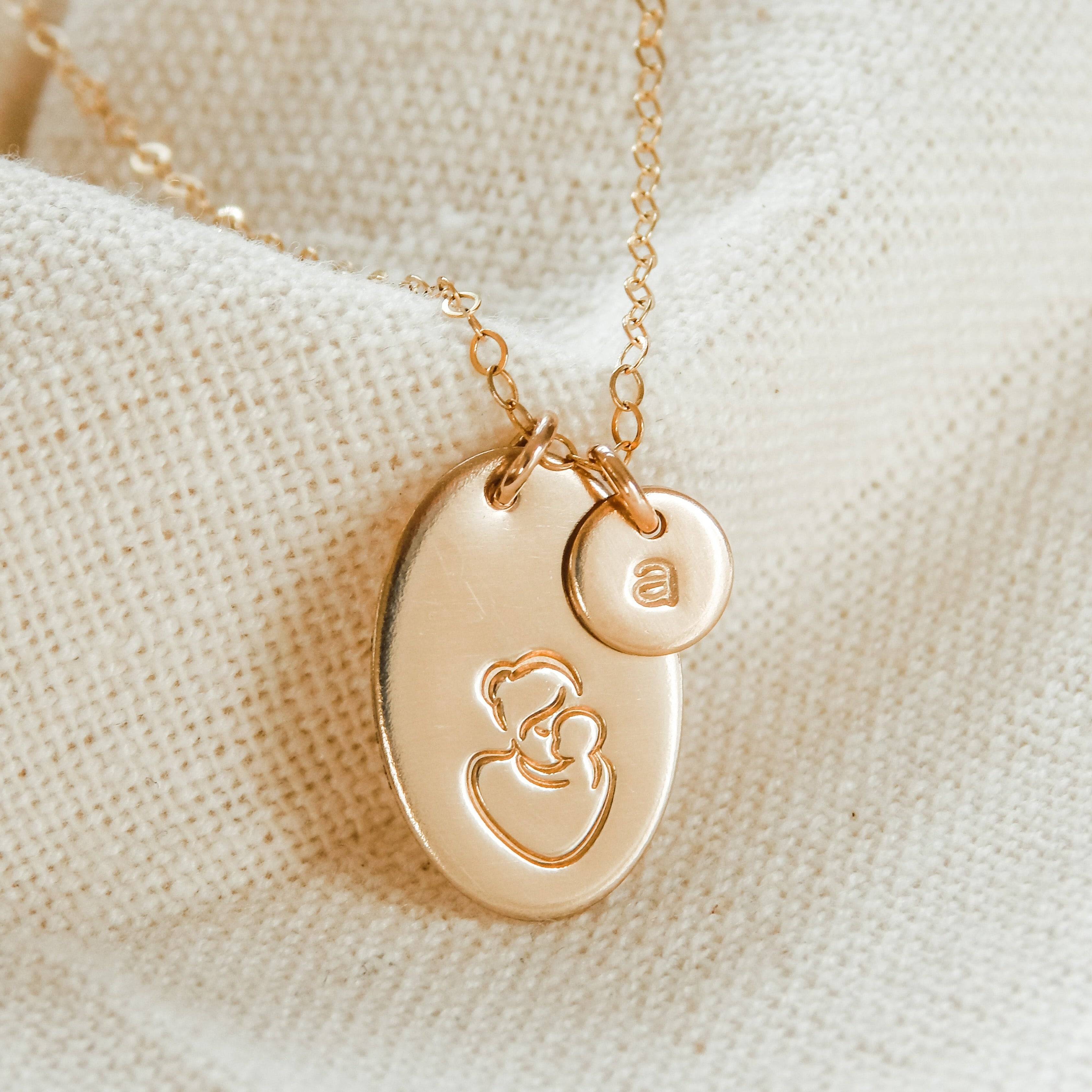 Hand Stamped Mother & Child Necklace by Barberry & Lace Jewelry featuring a 14k gold oval pendant with mother and child design and customizable initial charm.