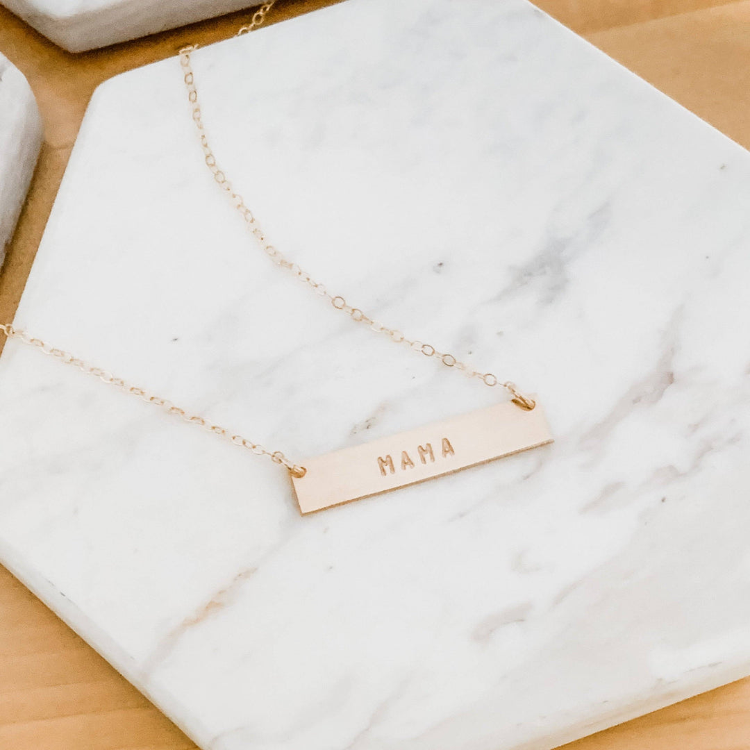 Hand Stamped MAMA Bar Necklace by Barberry & Lace Jewelry, 14k Gold Fill, displayed on a marble background, ideal for Mother's Day gifts.